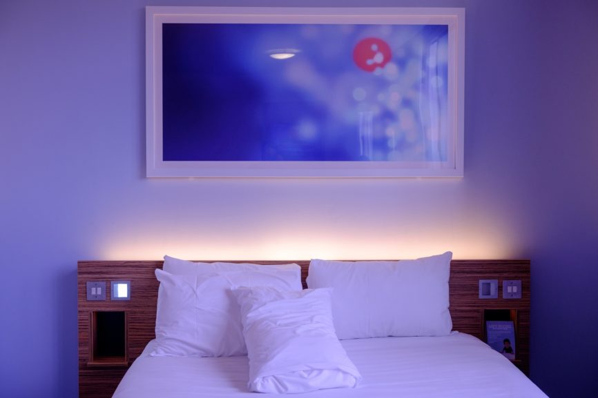 Osvětlená postel LED páskem a s obrazem na zdi