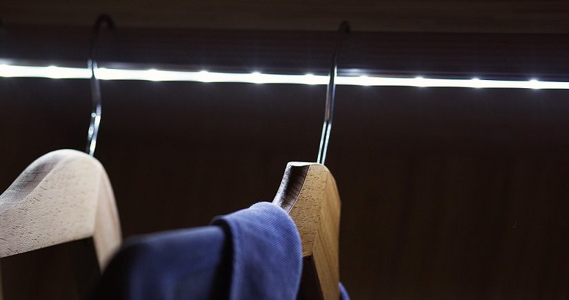 Osvětlená šatní tyč LED páskem s pověšeným oblečením